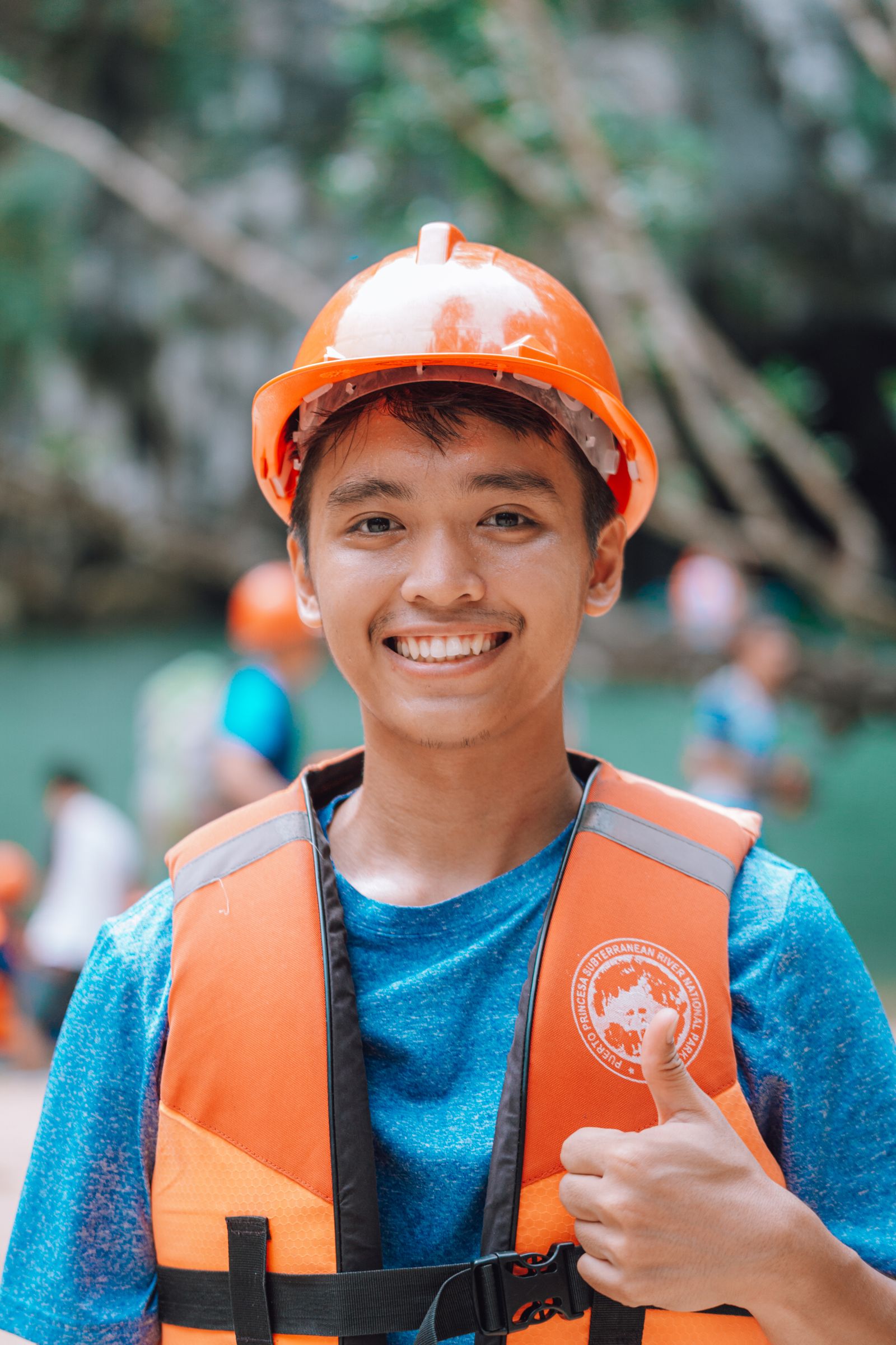 Trabalhador jovem sorrindo com capacete laranja e colete refletivo laranja