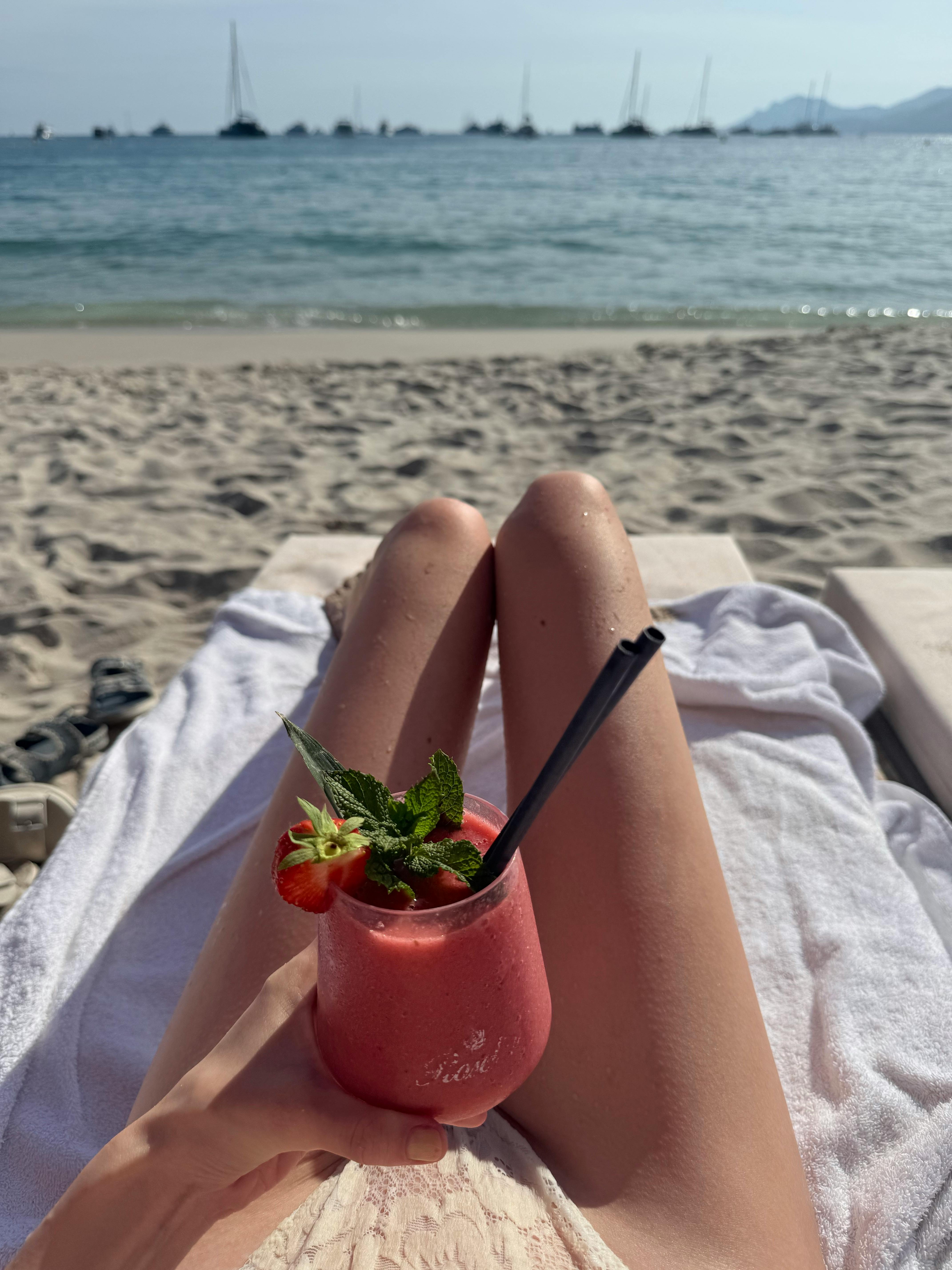 Free Enjoy a refreshing cocktail on a sandy beach with serene ocean views. Stock Photo