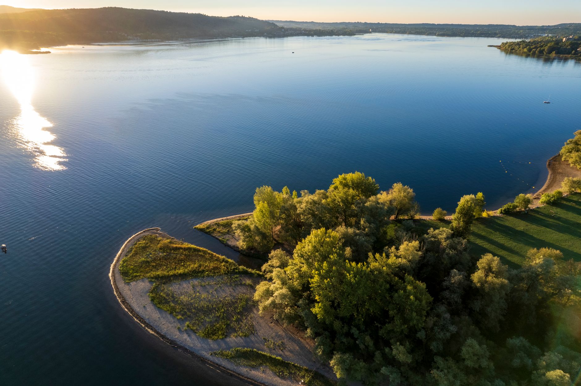 Aerial shot of Lake Varese with a peaceful shoreline at sunrise. Beautiful landscape view.