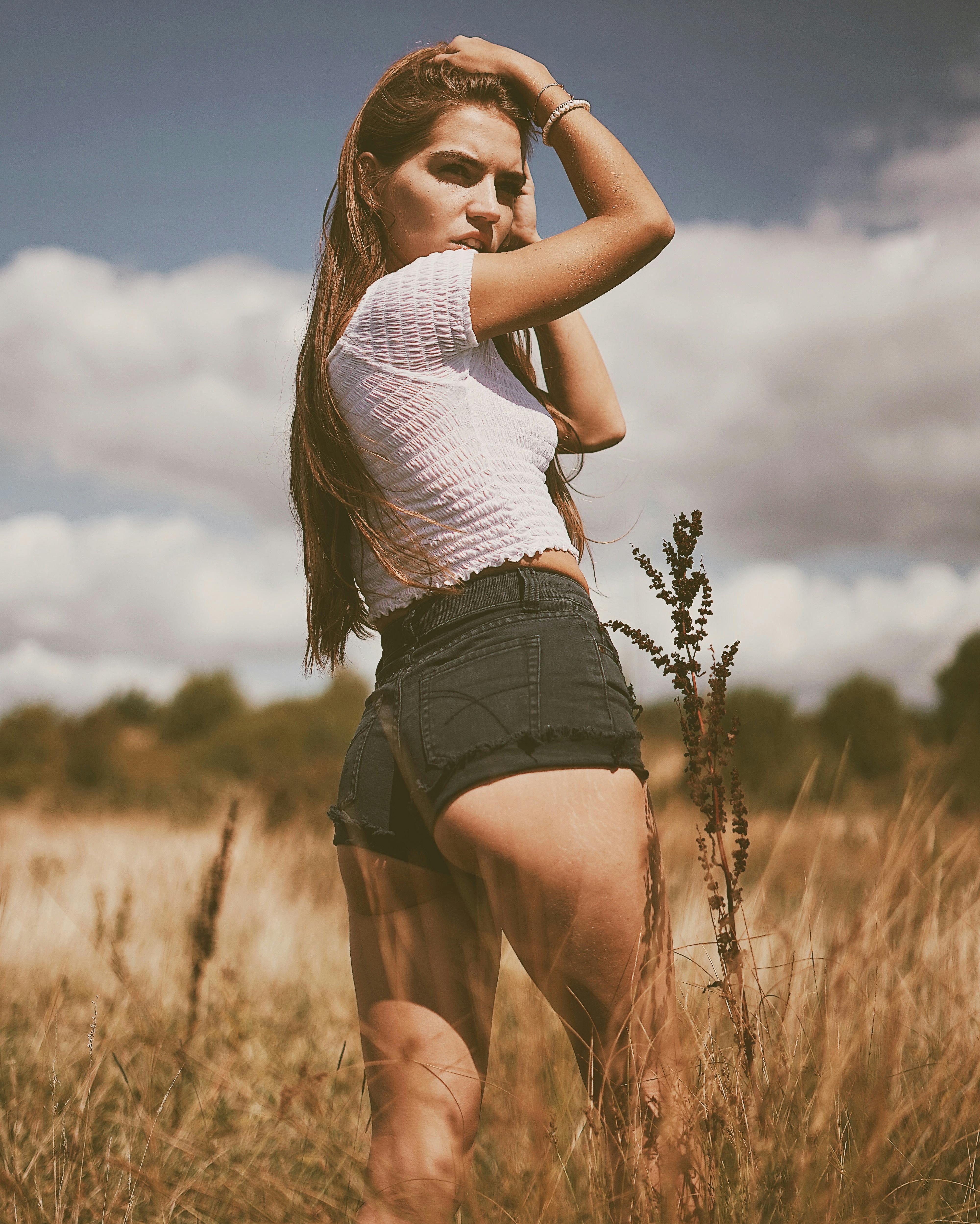 夏日田野中，一位身着休闲装的年轻女子在自然背景下摆姿势的户外肖像