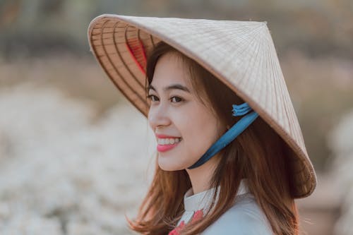 免費 微笑的女人，戴著柳條帽子選擇性焦點攝影 圖庫相片