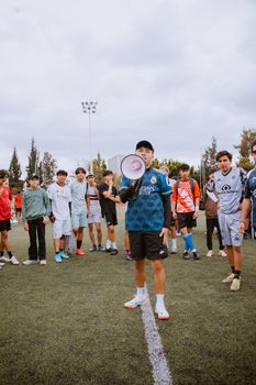 A football coach inspires his team with a megaphone on a field in Puebla, Mexico.