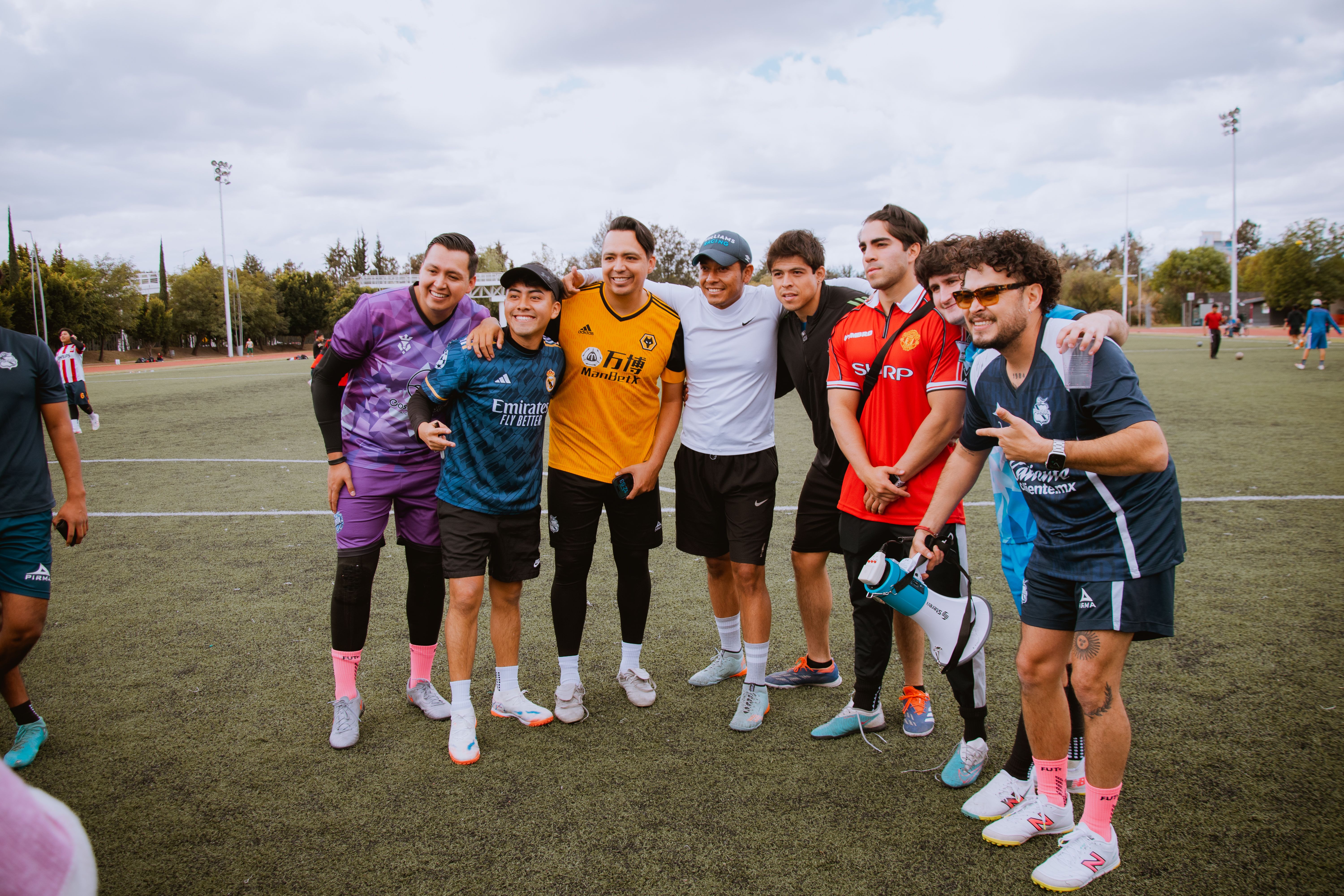 A group of friends gather on a football field in Puebla, Mexico, embracing for a photo.