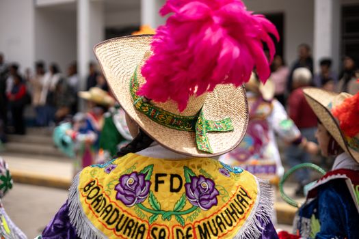Colorful festival attire with embroidered details and feathered hats in a lively celebration.
