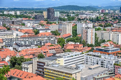 Free Aerial view capturing a vibrant urban cityscape with distinctive red roofs and distant mountains. Stock Photo