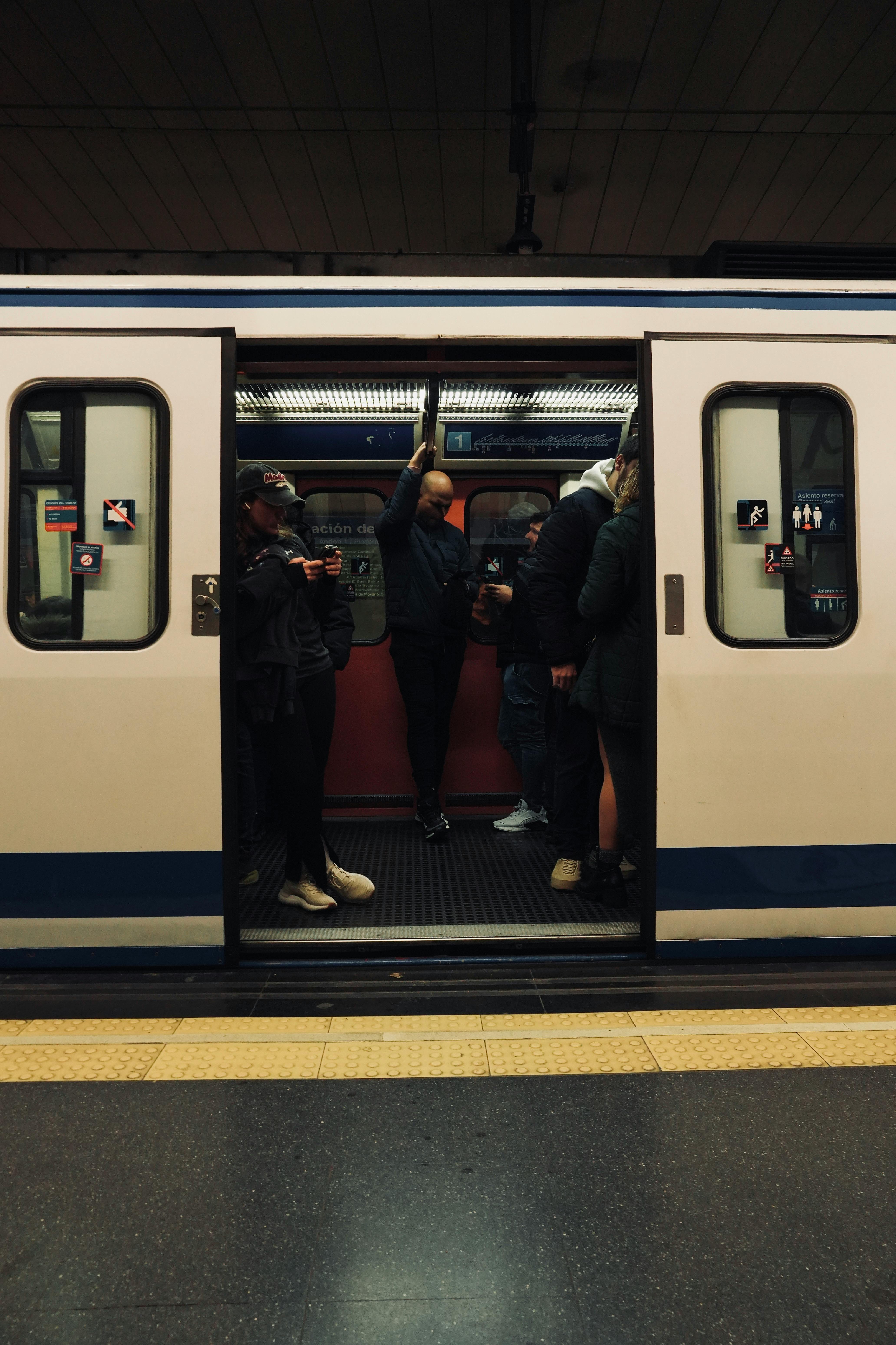 People standing inside an open subway train in a metro station.