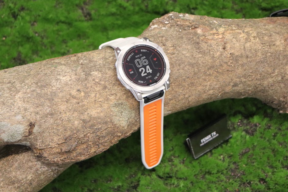Oura vs Withings: Sleep Tracking Accuracy Showdown Smartwatch with orange strap placed on a log outdoors, showcasing time and health features.