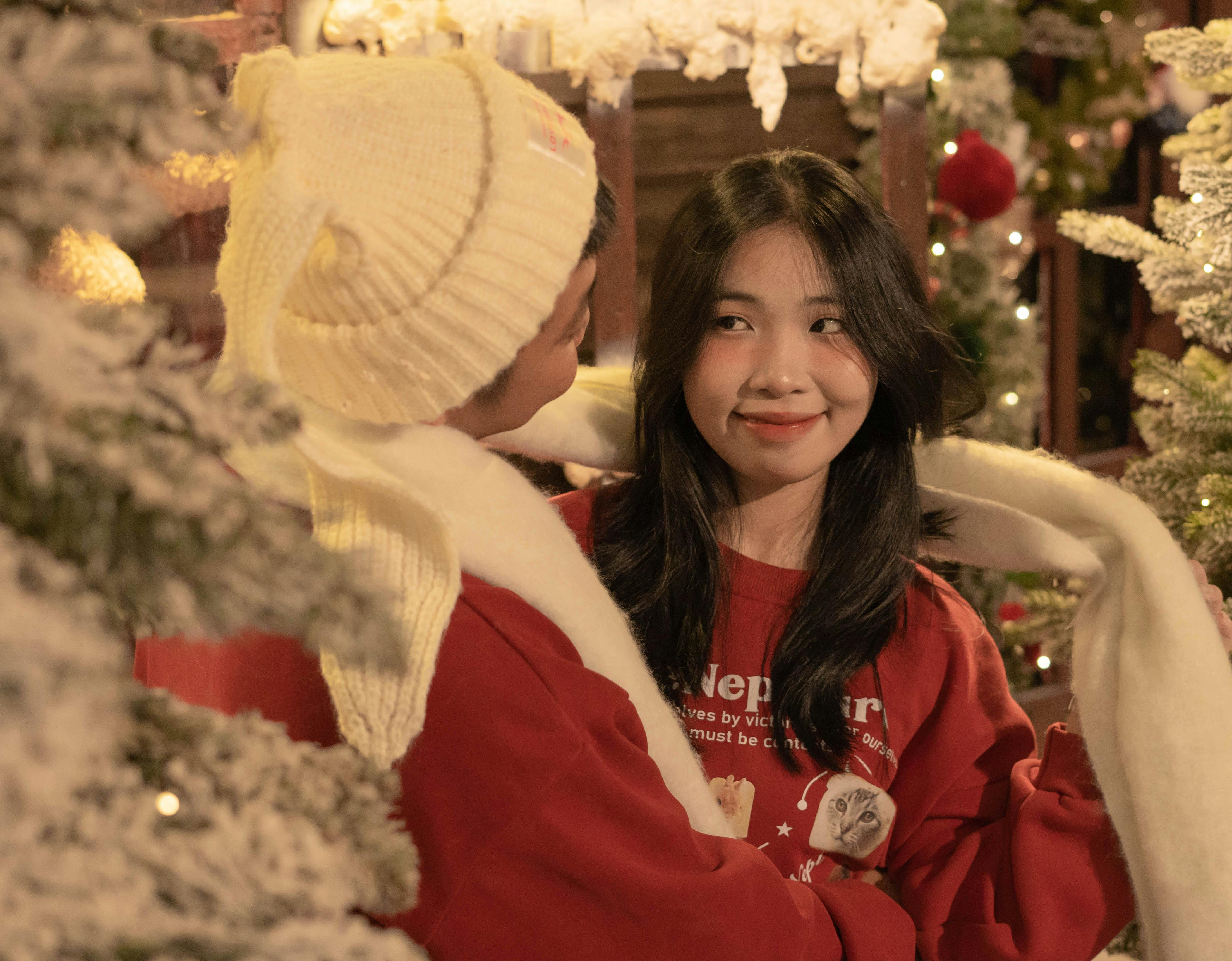 De franc Una parella alegre celebrant l'hivern entre decoracions festives i arbres coberts de neu. Foto d'estoc