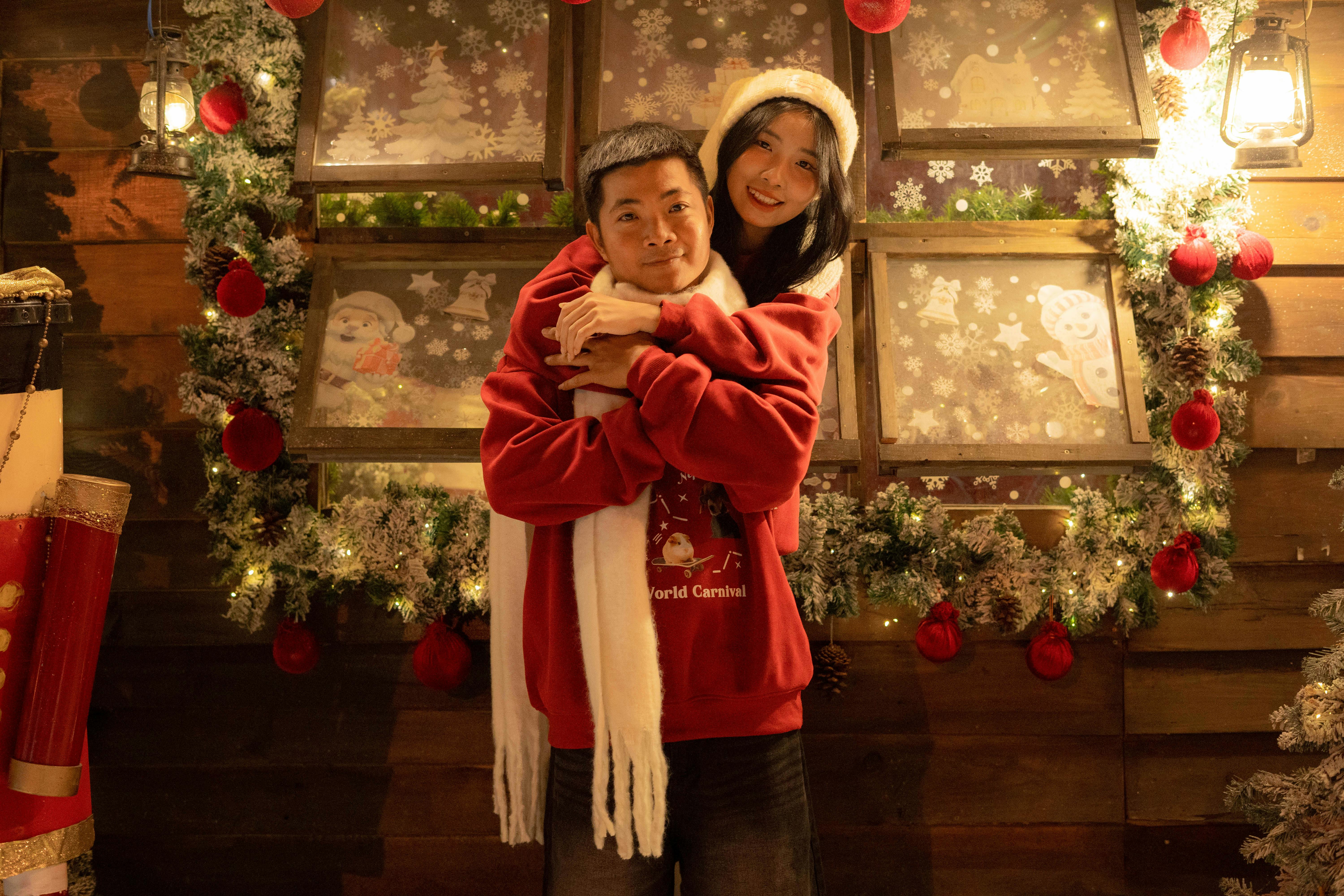 De franc Parella feliç amb jerseis vermells gaudint de les vacances a l'interior amb decoracions nadalenques festives. Foto d'estoc