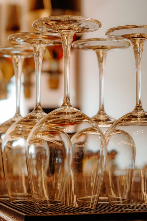 Free Close-up of upside-down wine glasses on a bar counter with a warm ambiance. Stock Photo