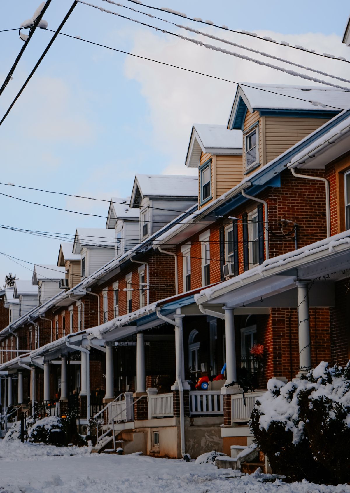 A row of brick porch-front rowhouses on a snowy Baltimore street