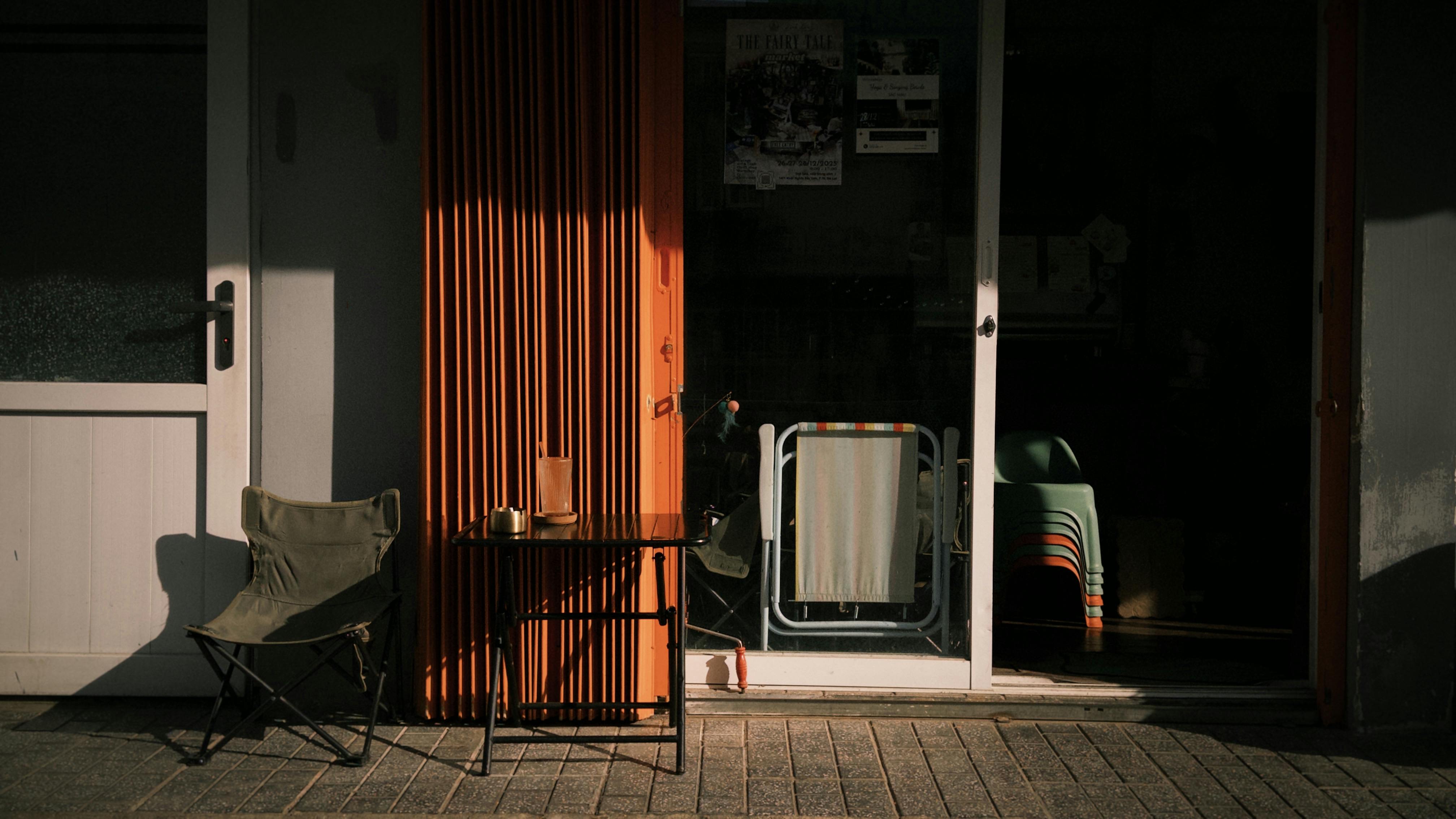 Gratuit Scaune și masă în aer liber, în lumina caldă a soarelui, în afara unei cafenele confortabile. Fotografie de stoc