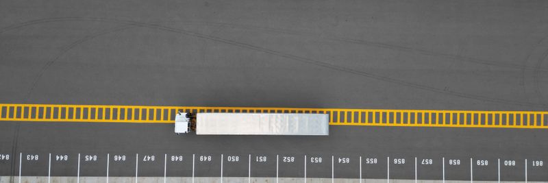 Top-down aerial image of truck trailers parked in a lot with distinct yellow markings.
