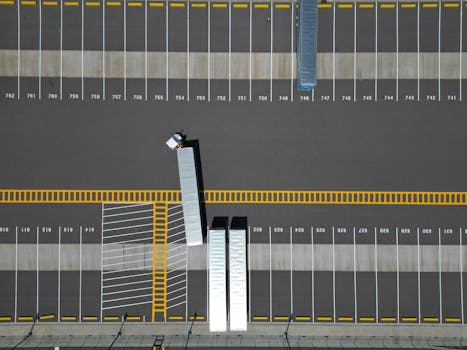 An aerial view of a large parking lot with lined spaces and semi-trucks.