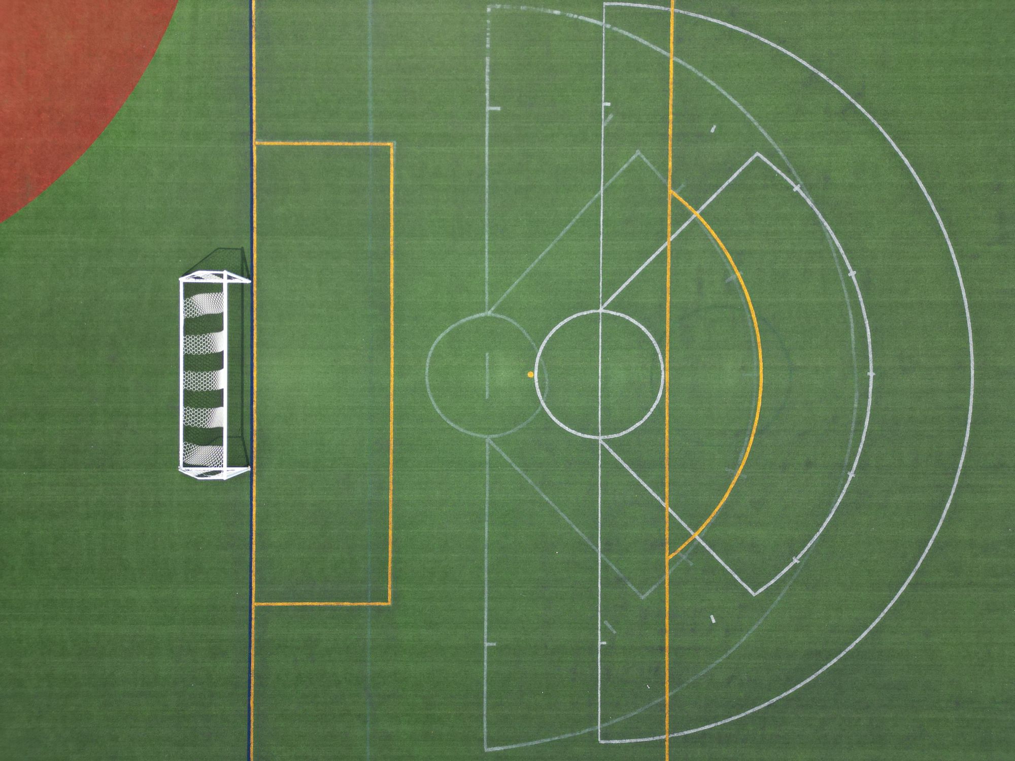 Aerial view of an empty soccer field showing a goal post and field markings.
