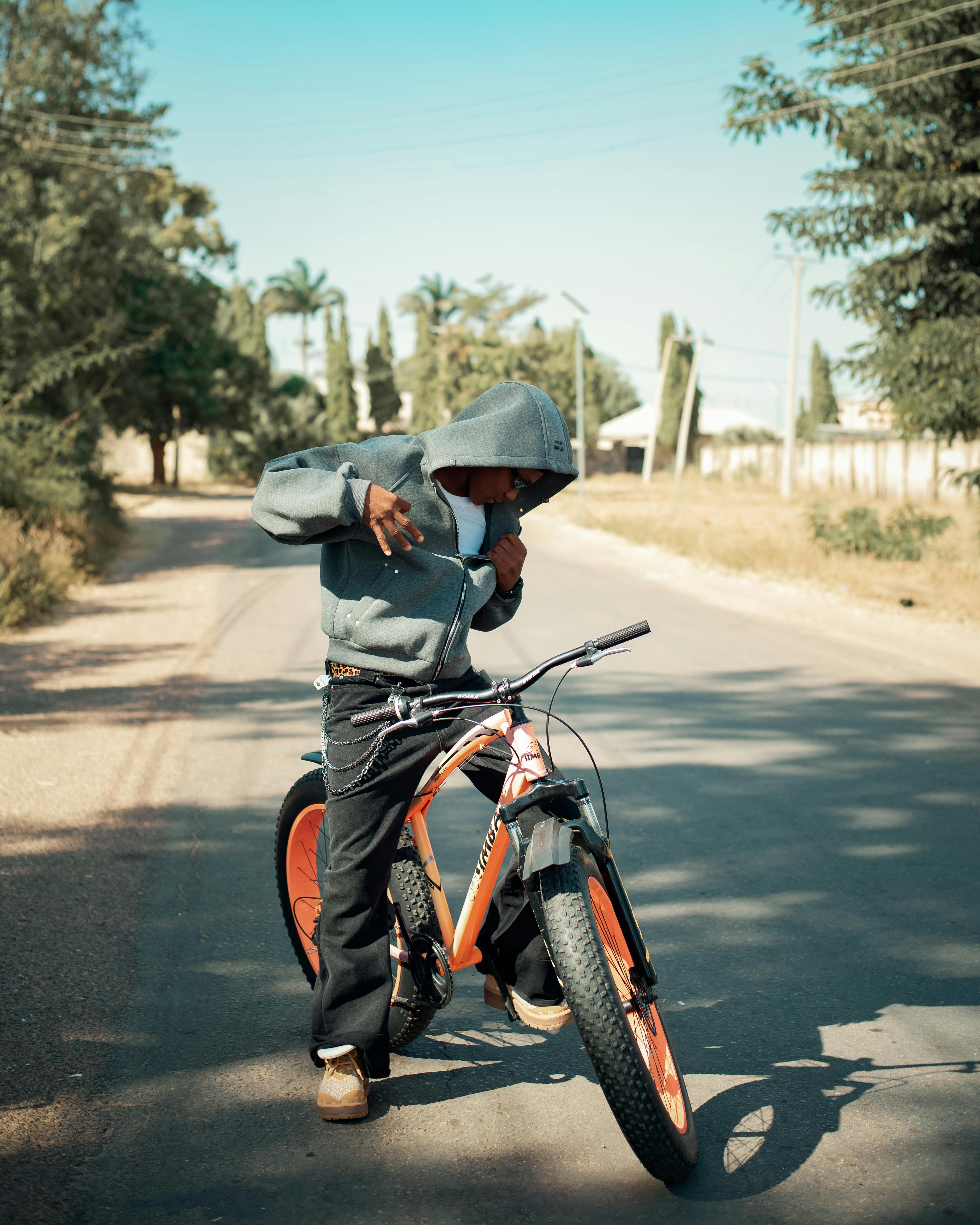 De franc Un jove posa amb una bicicleta en un dia clar i assolellat en un carrer suburbà. Foto d'estoc