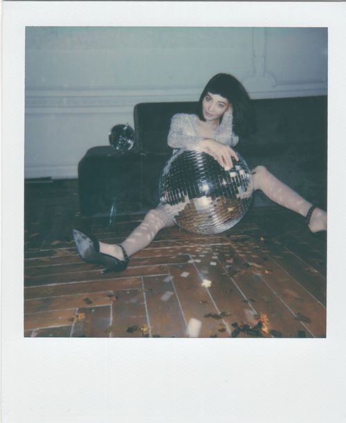 Free Stylish woman posing with a mirror ball in a vintage indoor setting. Stock Photo