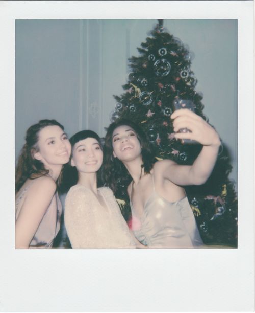Free Three women take a joyful Christmas selfie in front of a festive tree indoors. Stock Photo