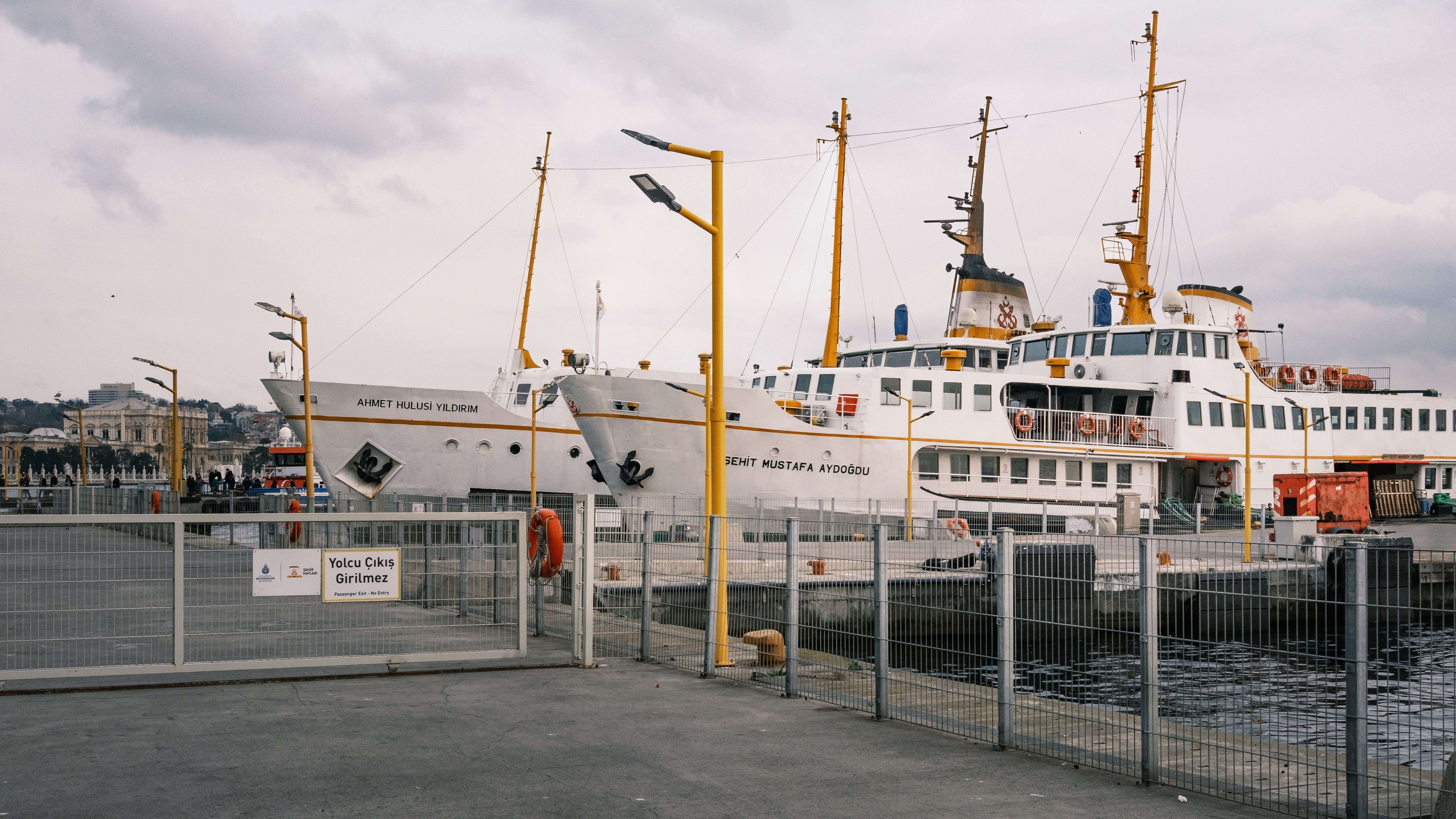 Two passenger ferries moored at a dock in Istanbul with overcast skies.