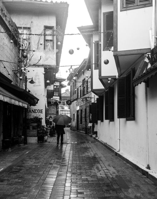 Free Charming European alleyway under rain, person with umbrella. Stock Photo