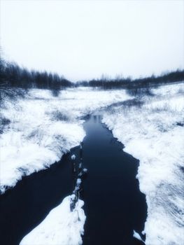 A peaceful snow-covered river winding through a winter landscape, evoking tranquility.