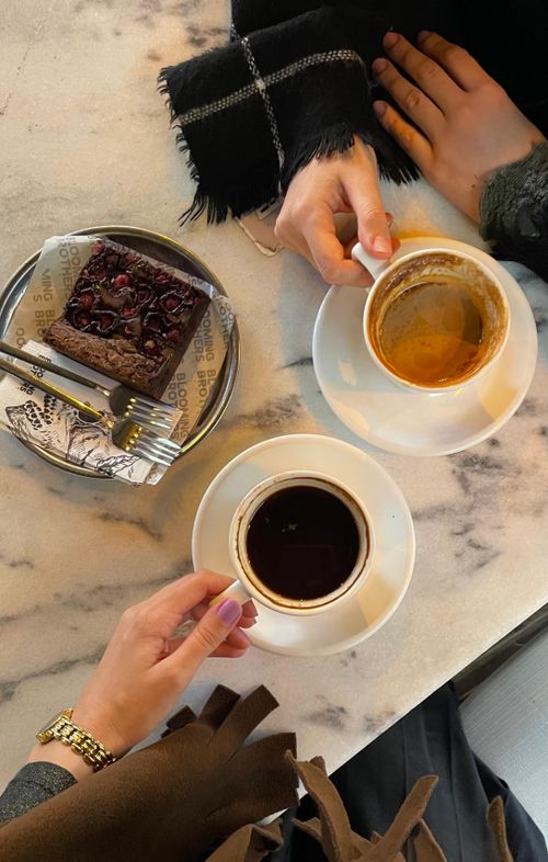 Free Overhead shot of two people enjoying coffee and chocolate cake at a cafe. Stock Photo
