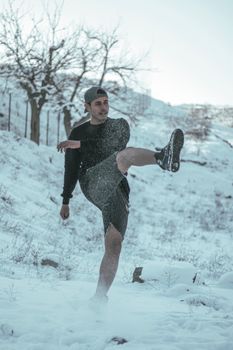 Young man kicking up snow in a wintery outdoor scene, showcasing energy and movement.