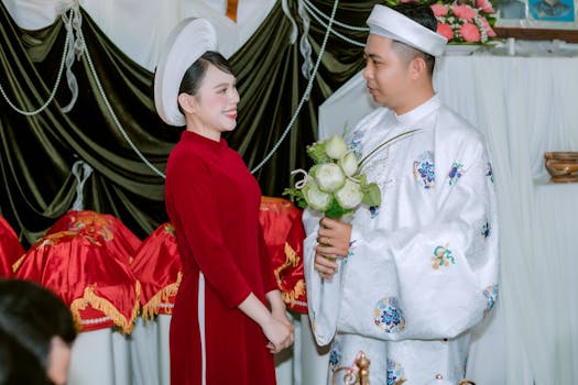 Couple in traditional Vietnamese attire during a wedding ceremony, exchanging smiles.