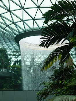 Majestic indoor waterfall surrounded by lush tropical plants, featuring a modern architecture dome.