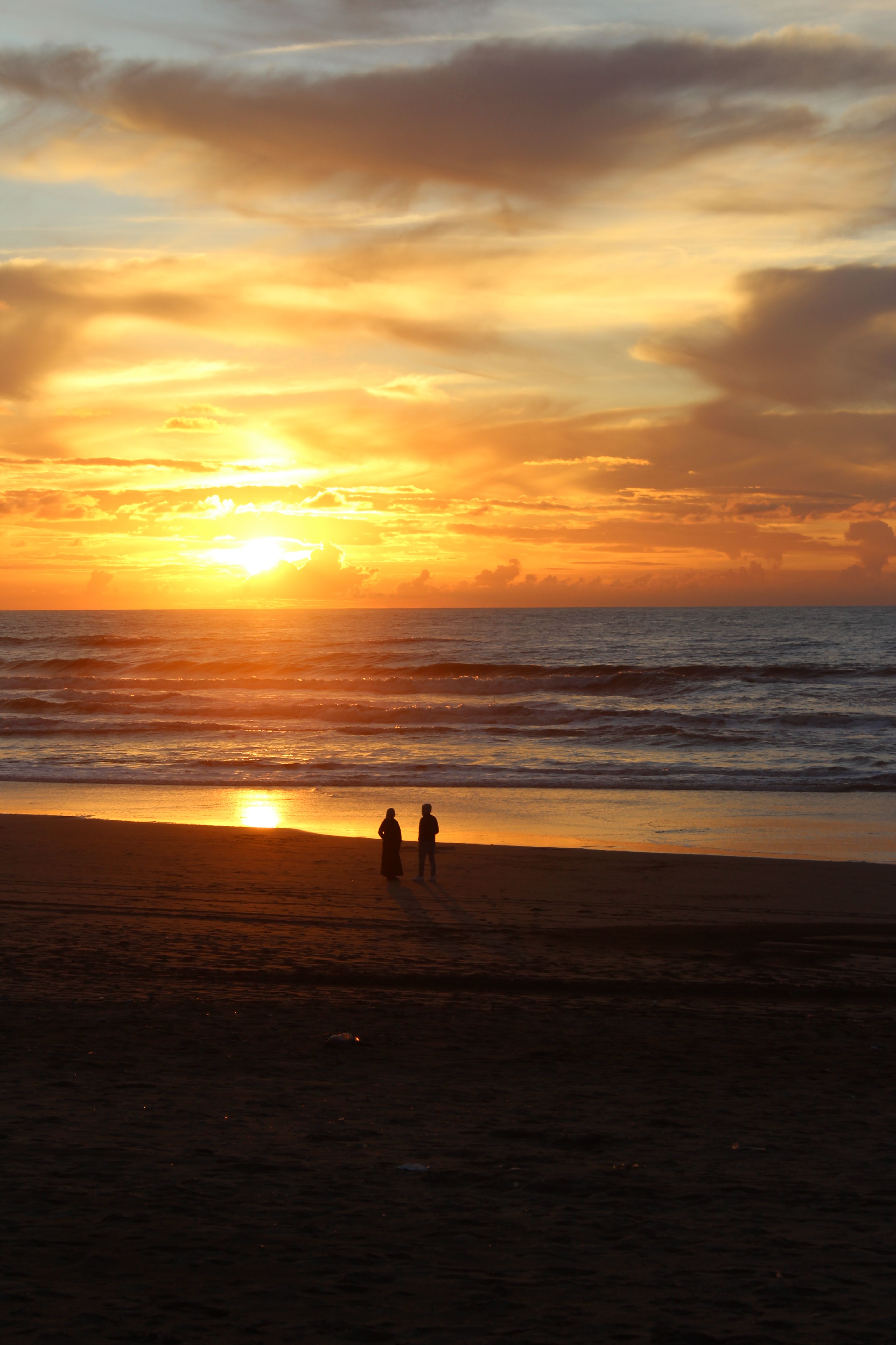 Scenic Beach Sunset with Silhouetted Couple · Free Stock Photo