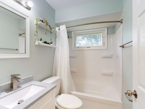 Elegant contemporary bathroom with white fixtures and natural light.