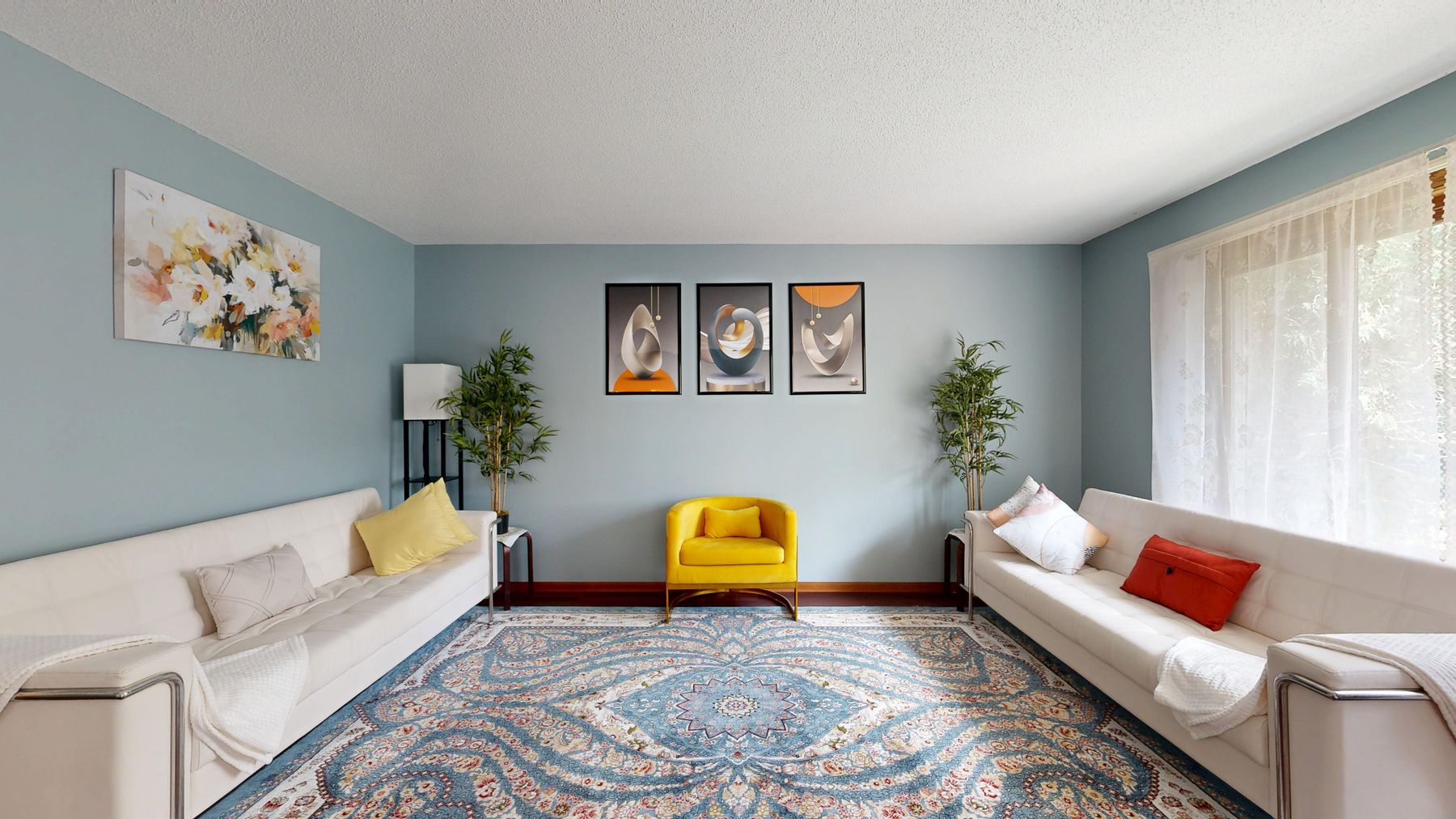 Powder blue living room with two pale sofas, yellow chair, red cushion, patterned rug, daylight and framed art