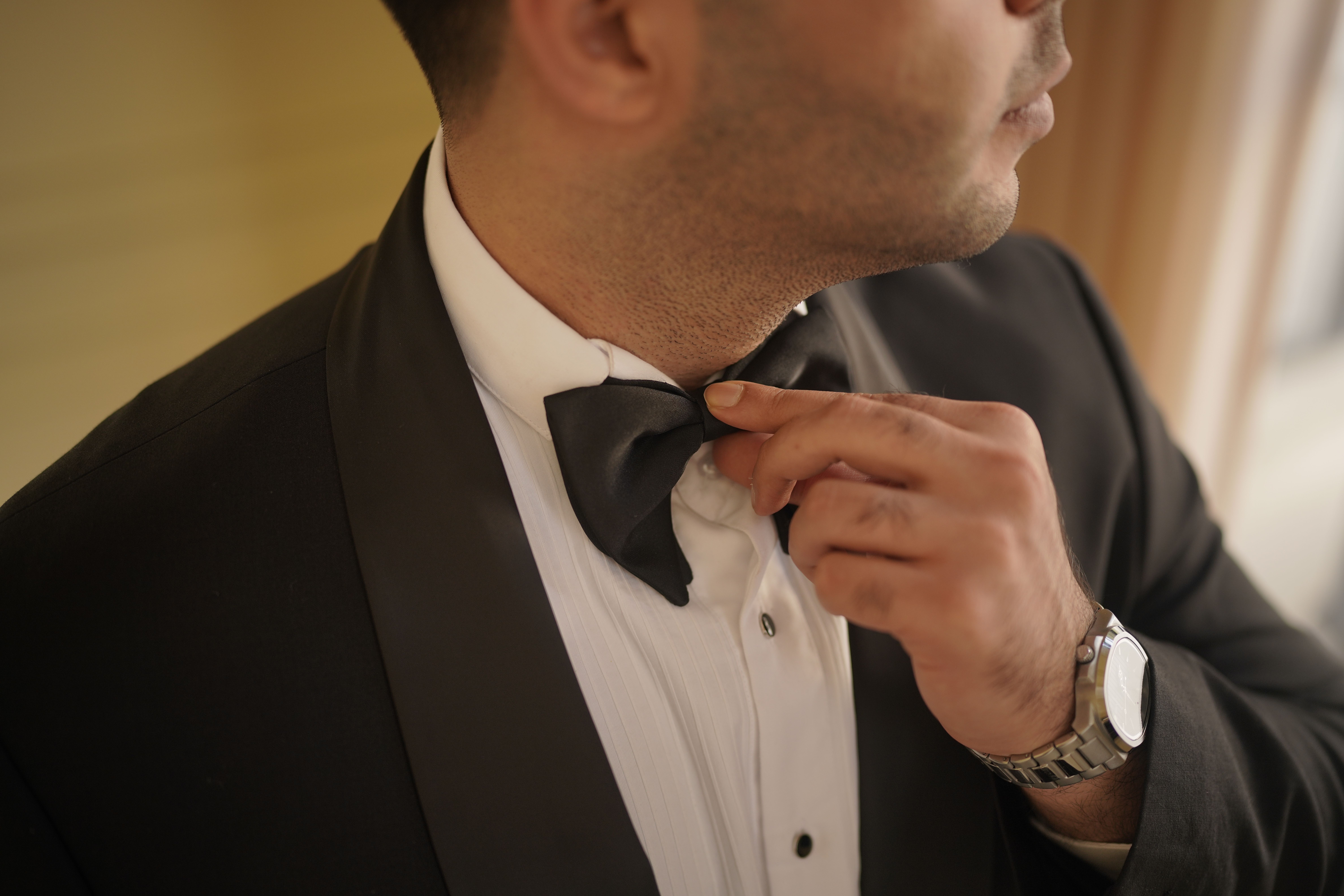 Groom adjusting bow tie in an elegant tuxedo