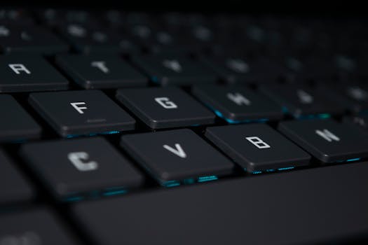 Detailed view of a black laptop keyboard with blue backlighting, showcasing modern technology.