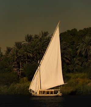 A serene scene of a traditional felucca boat sailing along the lush banks of the Nile River.