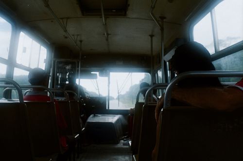 Free View from inside a crowded bus with seated passengers on a daytime journey in a city. Stock Photo
