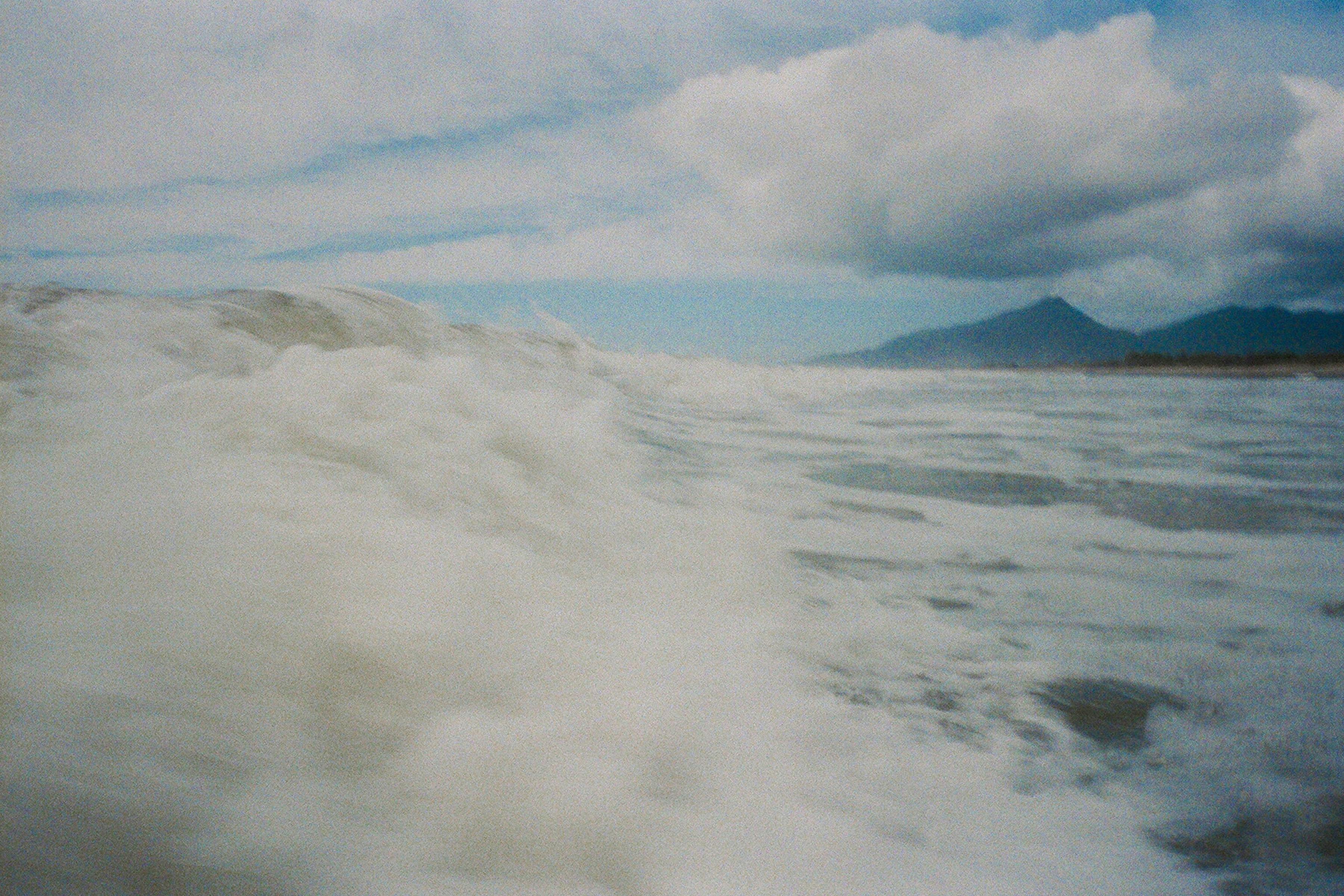 在遥远的岛屿附近，海浪在多云和暴风雨的天空下撞击，景色迷人