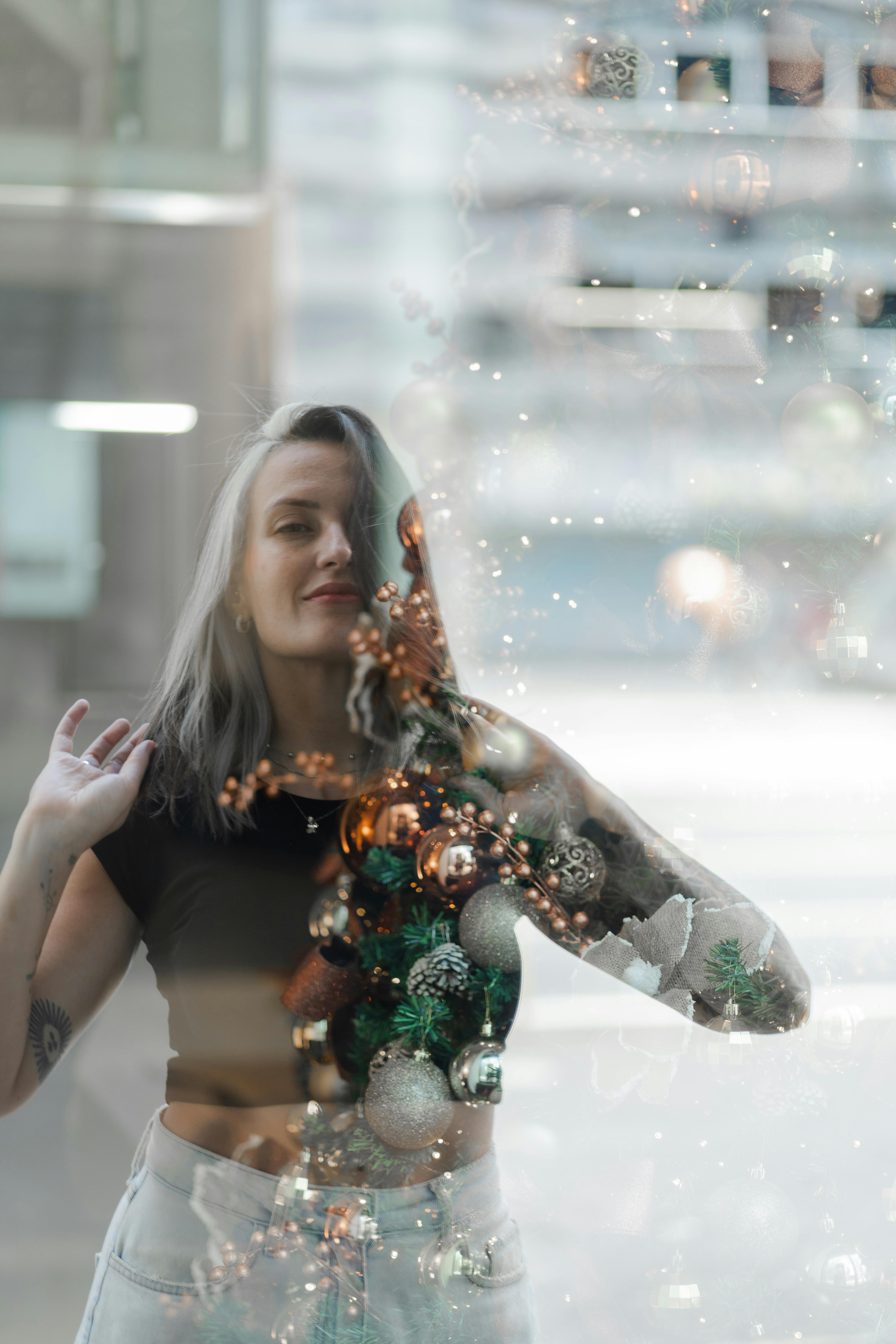 De franc Foto artística d'una dona reflectida en una finestra amb decoracions nadalenques. Foto d'estoc