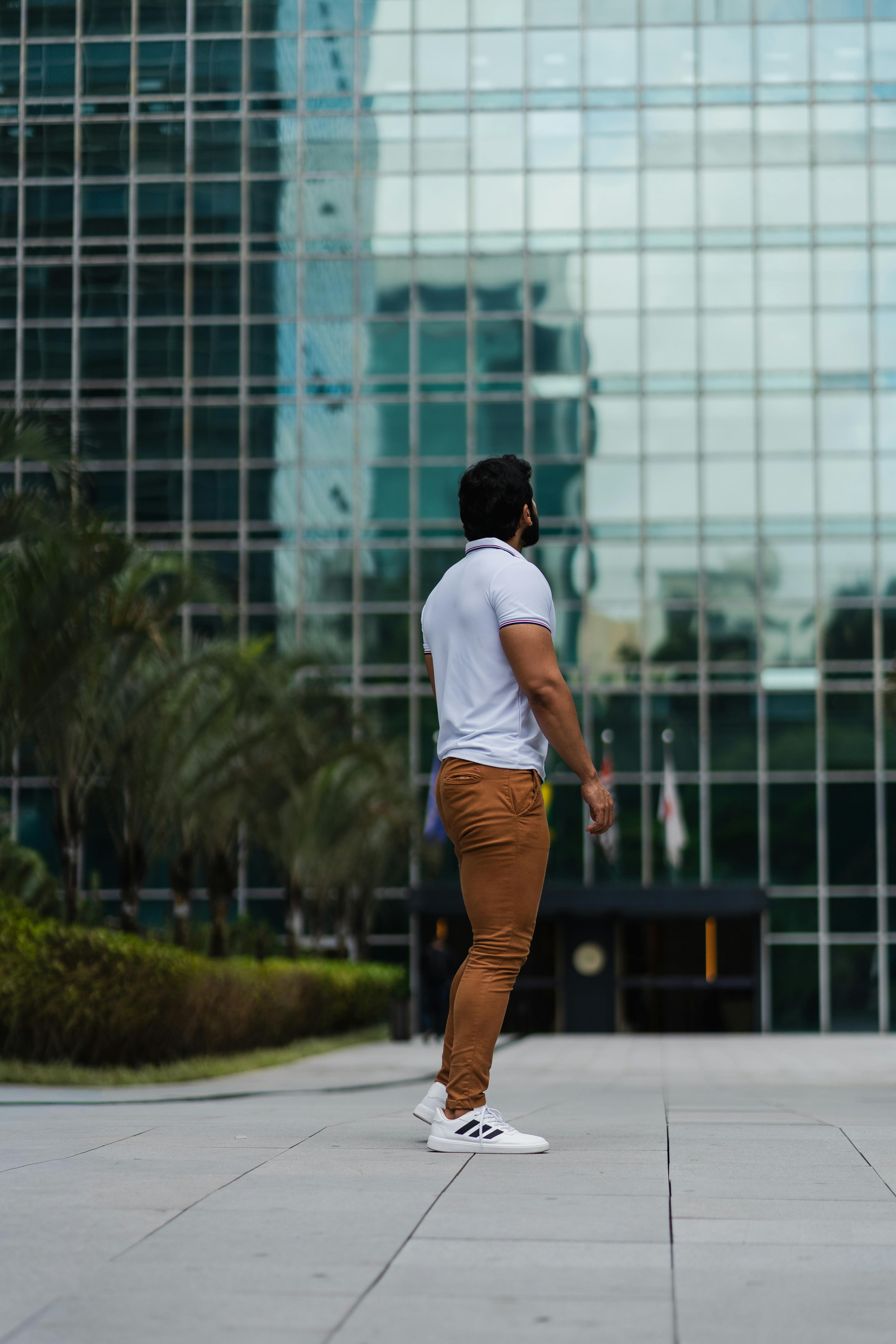 De franc Home caminant pel districte comercial urbà amb un edifici de vidre com a teló de fons, fotografia diürna. Foto d'estoc