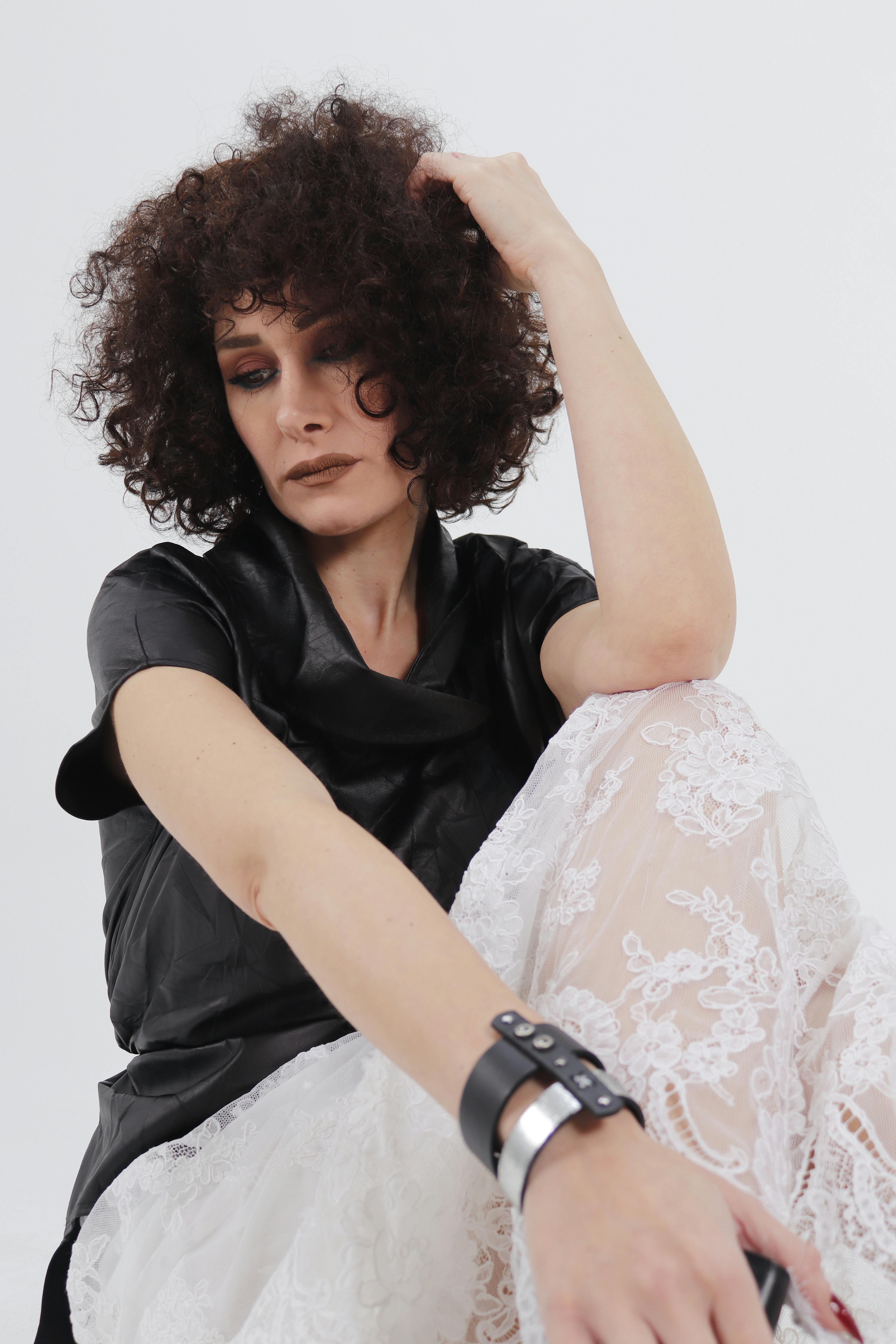 Bezpłatne Stylowy portret modelki w koronce i skórze z fryzurą afro, wykonany w pomieszczeniu. Zdjęcie z galerii