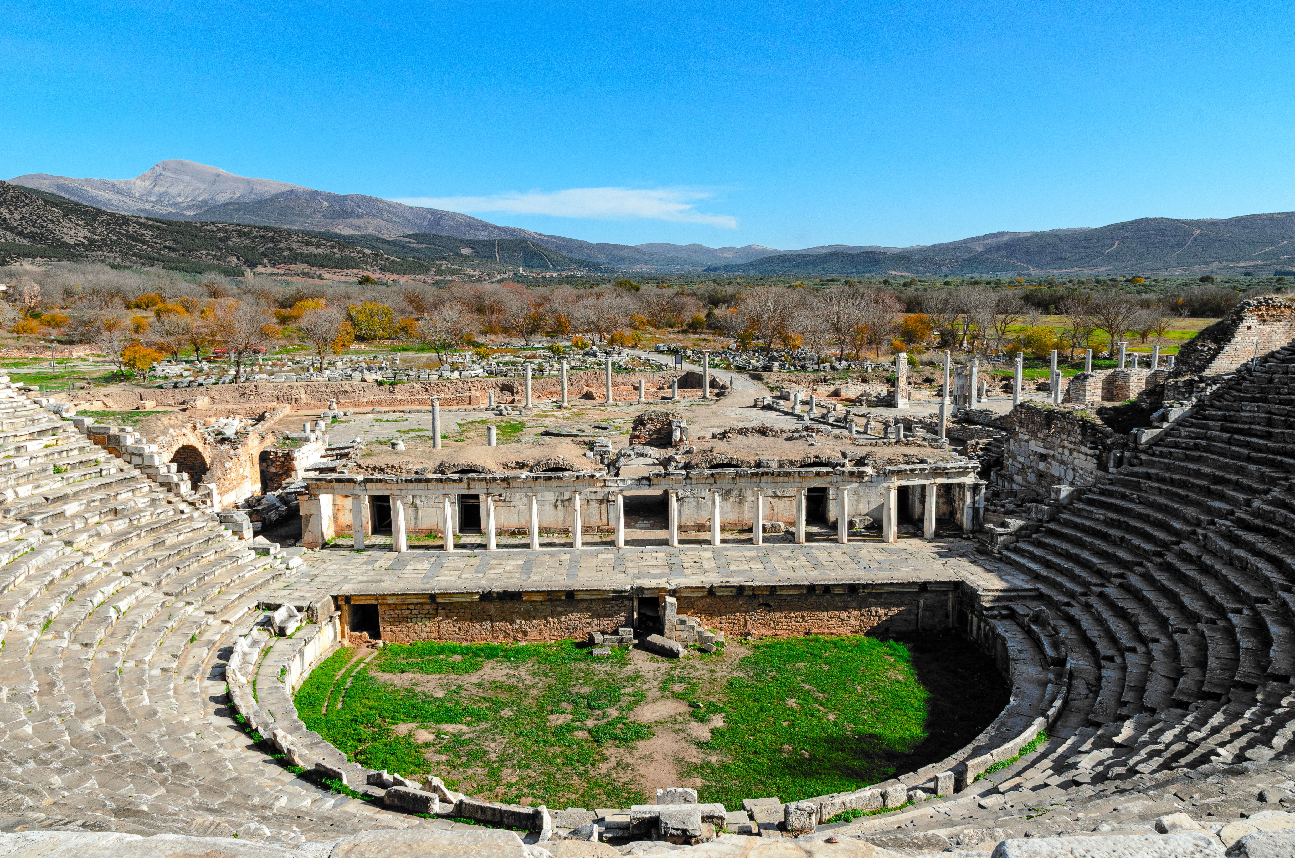 Stone remains and columns of an ancient Greek-Roman style outdoor theater.