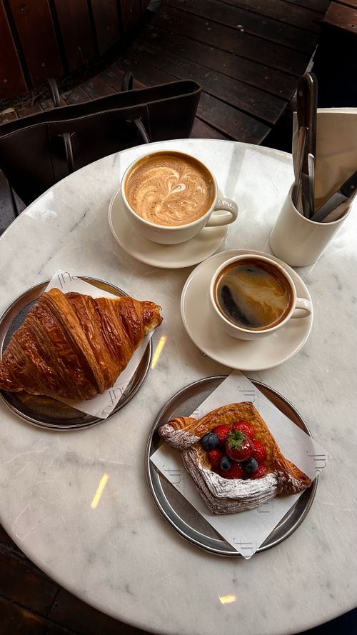 Free Elegant breakfast setting featuring a croissant, fruit pastry, and two coffee cups. Stock Photo