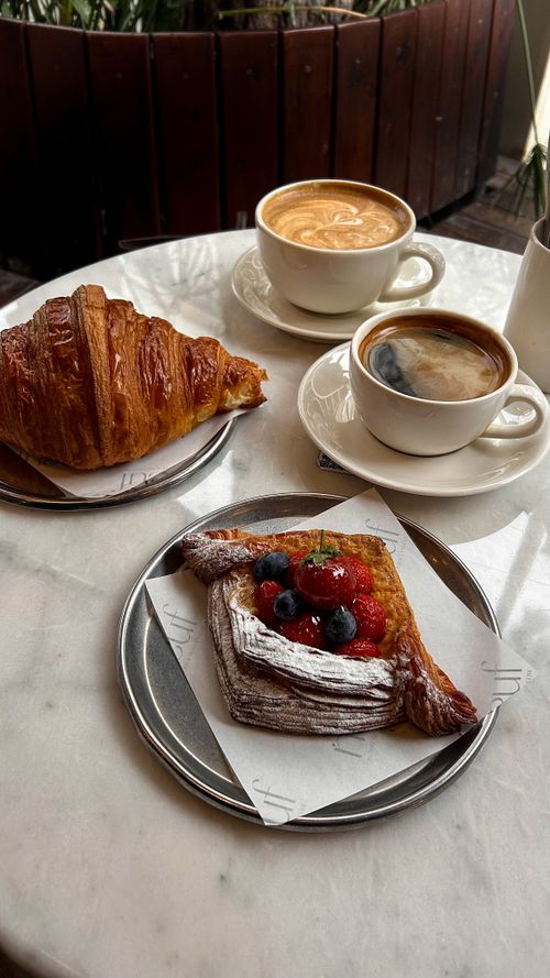 Free Captivating morning scene with coffee, croissant, and berry pastry on a marble table. Stock Photo
