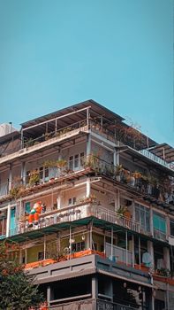Vibrant cityscape with urban apartment building and lush balconies under a clear blue sky.