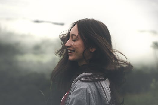 在雾气缭绕的户外场景中，一位微笑的女人的肖像捕捉到了宁静与自然的本质