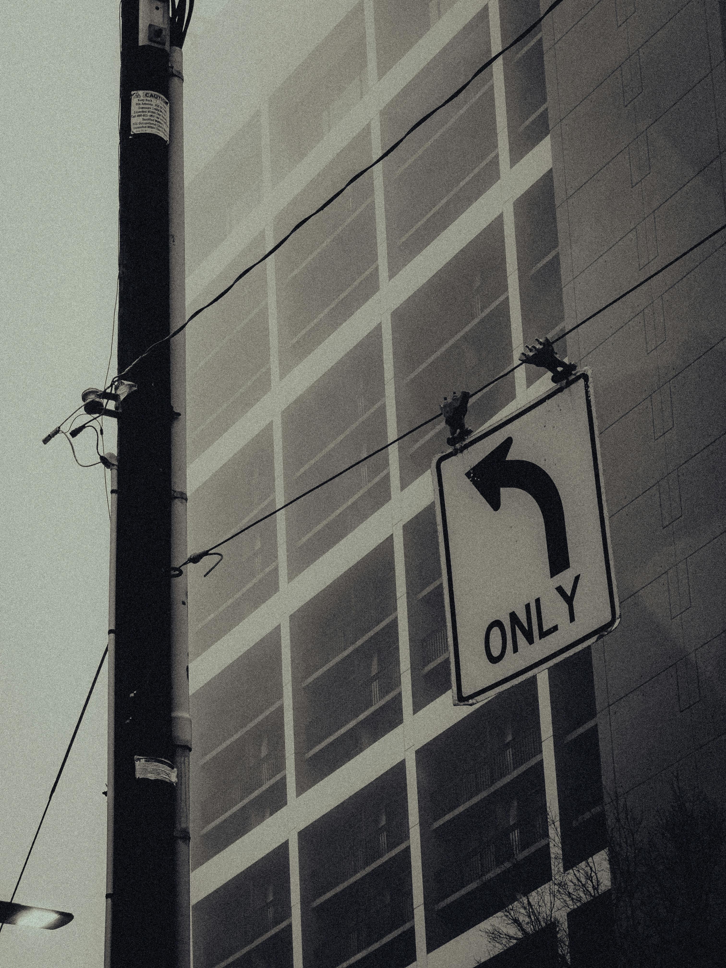 Zadarmo Umelecká mestská fotografia s odbočovacou značkou vľavo a zahmlenou fasádou budovy. Fotka z fotobanky