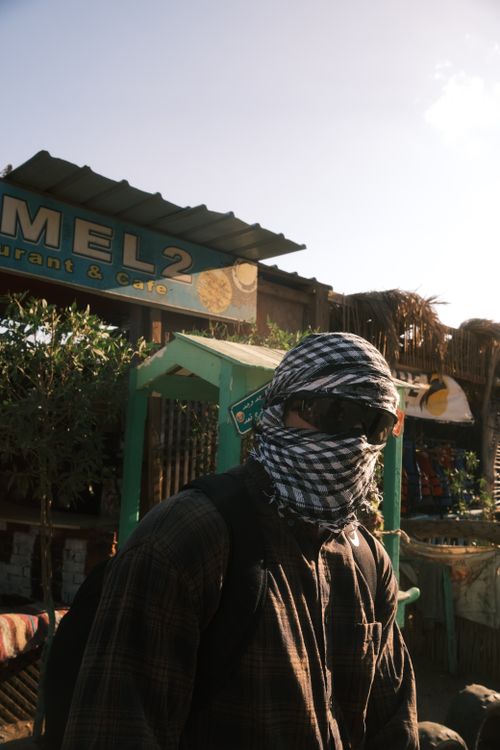 Free Person wrapped in scarf and sunglasses in front of Dahab's Camel Café, Sinai, Egypt. Stock Photo