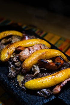 Delicious grilled meat and ripe plantains served on a hot stone platter.