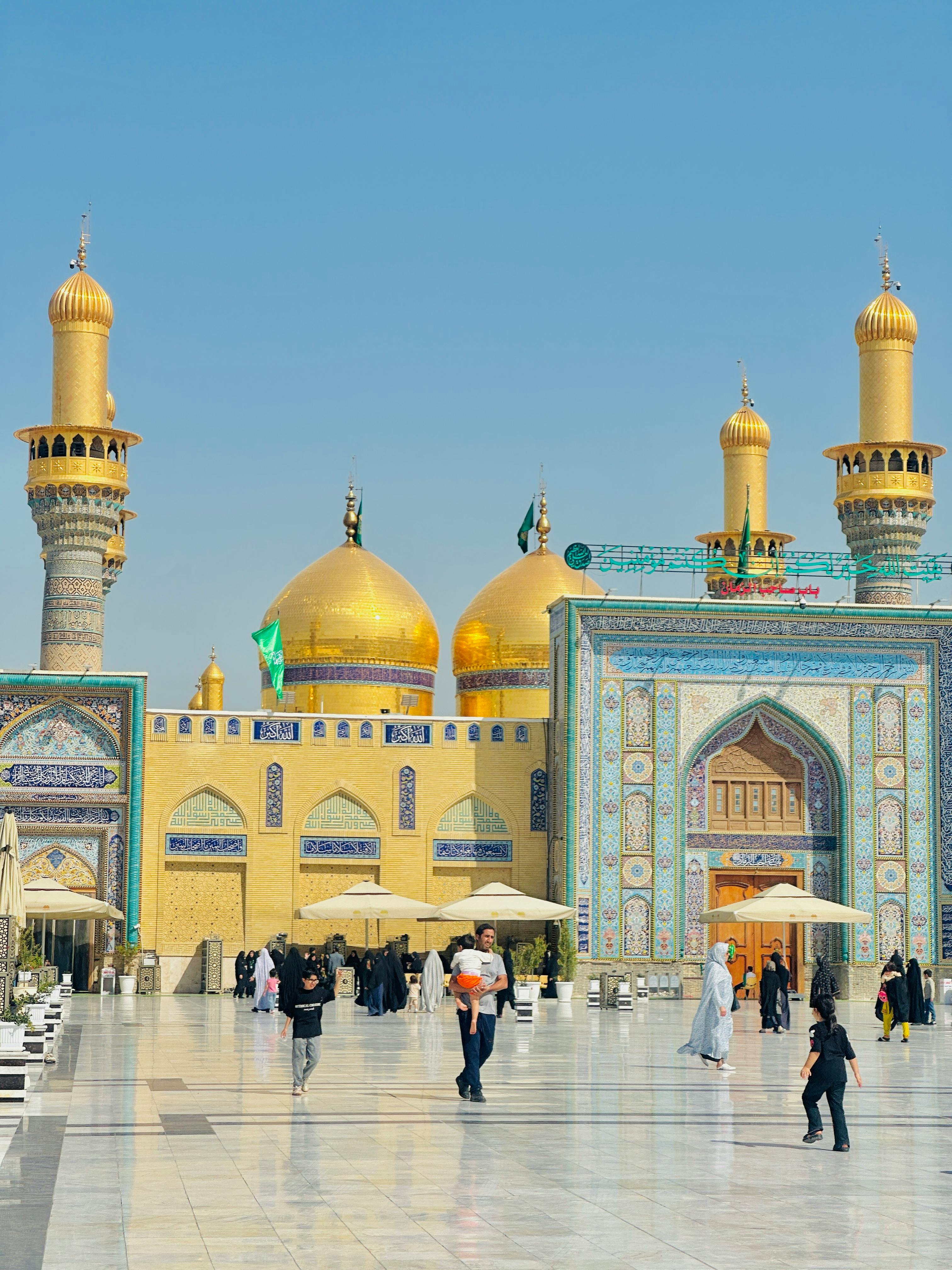 Stunning view of the Imam Ali Shrine with its golden domes and bustling visitors in Najaf, Iraq.