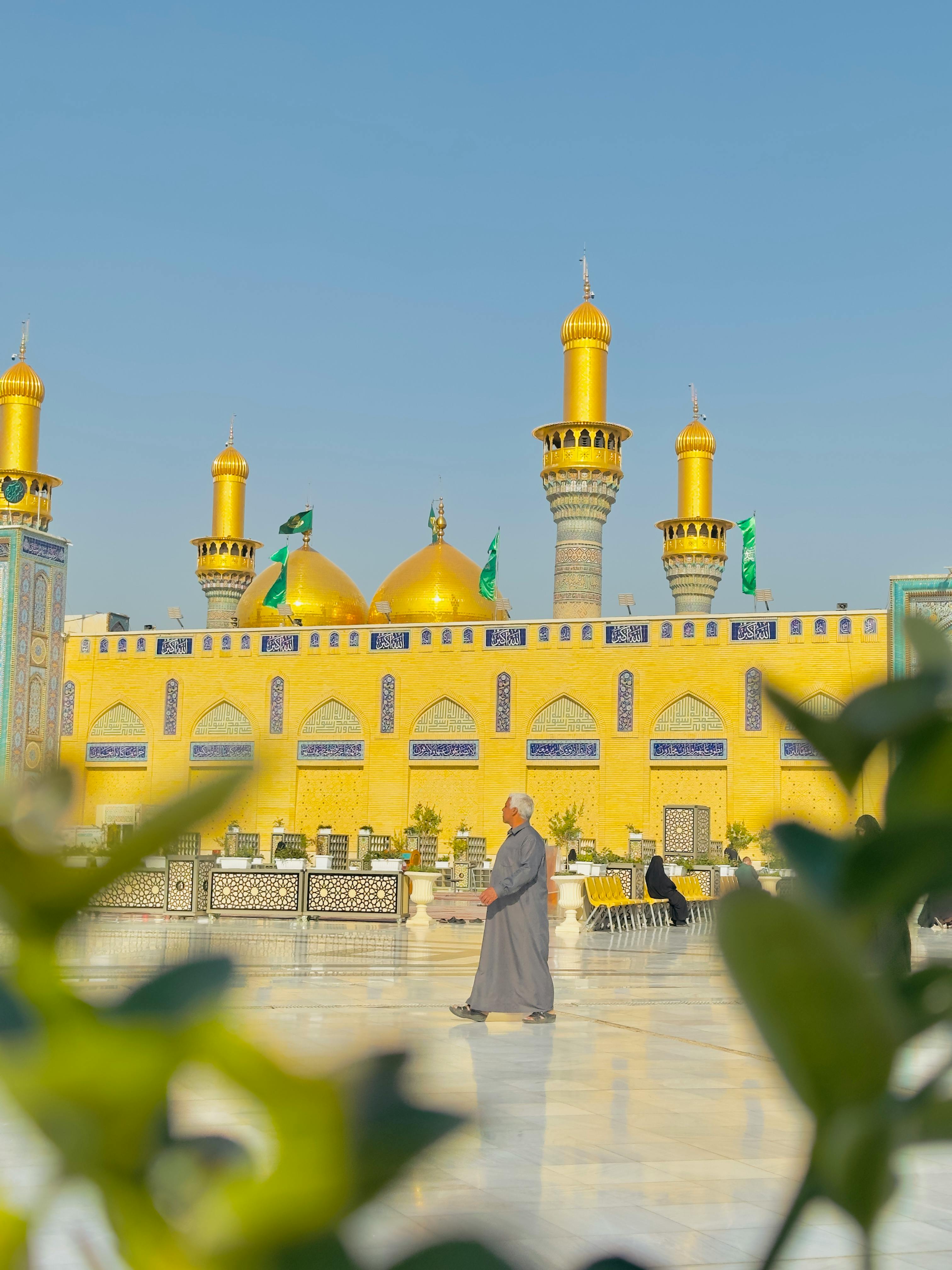 A stunning view of a golden mosque featuring classic Islamic architecture under a clear blue sky.